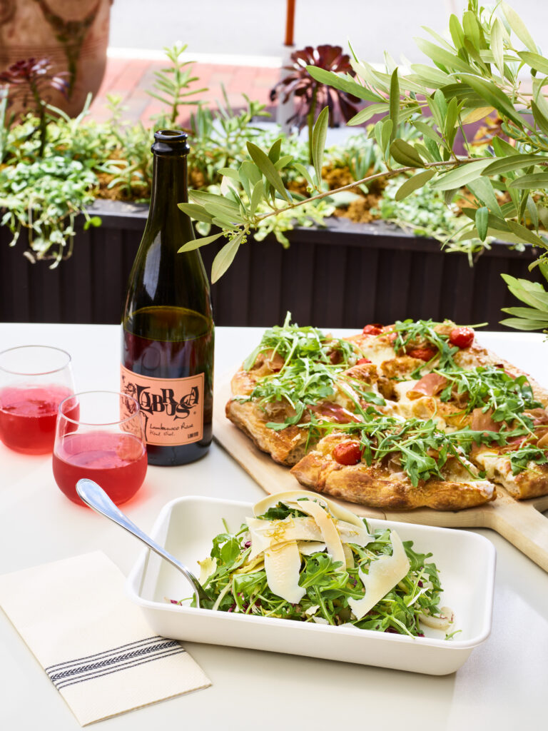 Roman style pizza, arugula salad, and Lambrusco served al fresco at Roma Alla Pala